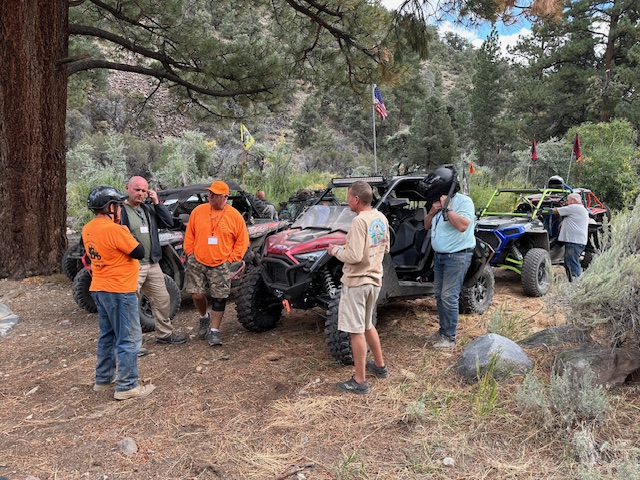 Riders chatting and relaxing under pine trees on the trail